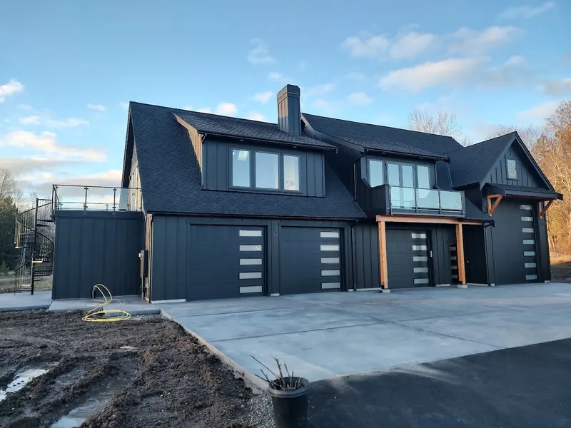 Black board-and-batten shop with modern garage doors