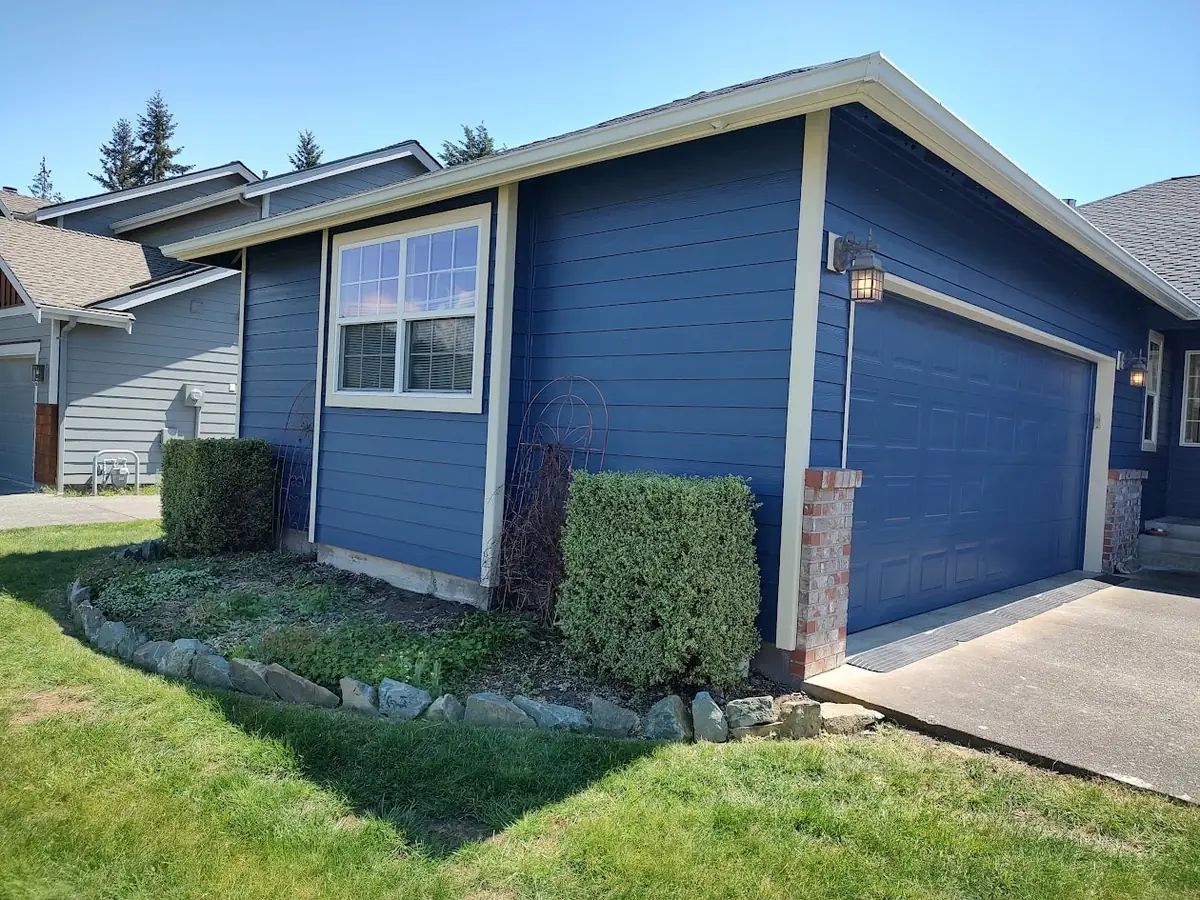 Blue house and garage door with cream trim, repainted by our crew