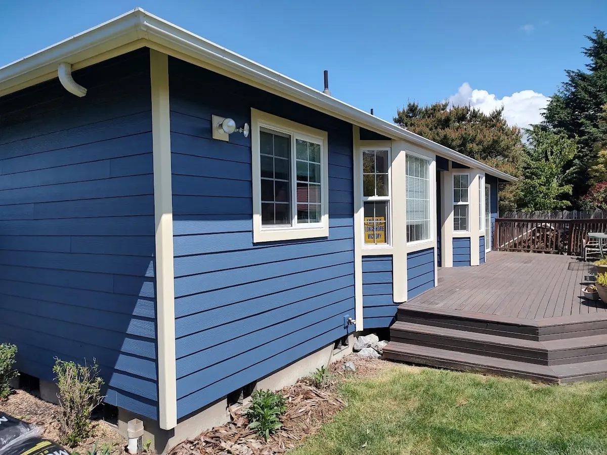 Blue house with cream trim beside a back deck, repainted by our crew
