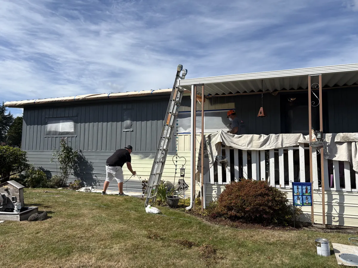 Our crew spraying a house exterior from a ladder