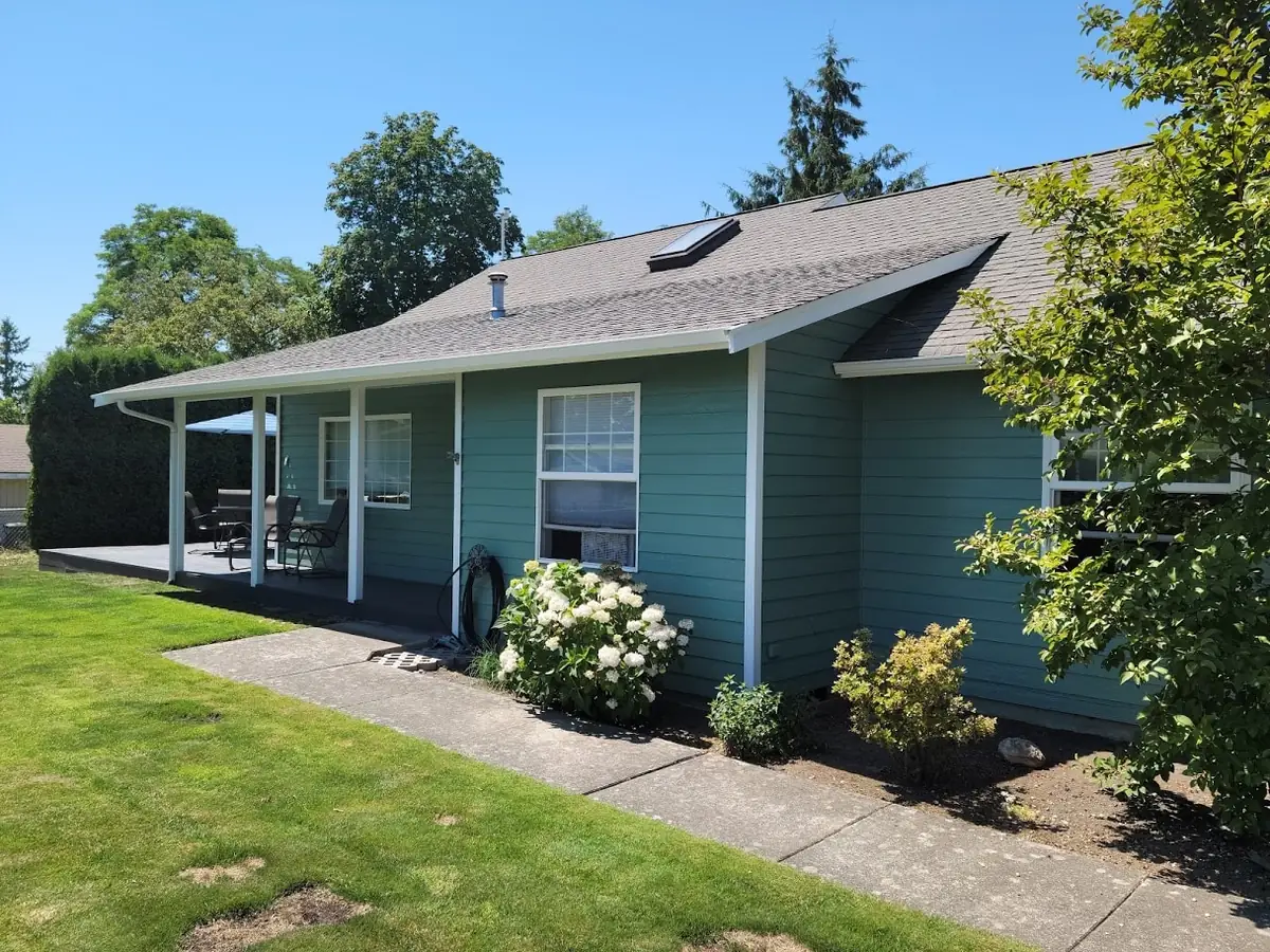 Teal house with white trim and a lawn, repainted by our crew