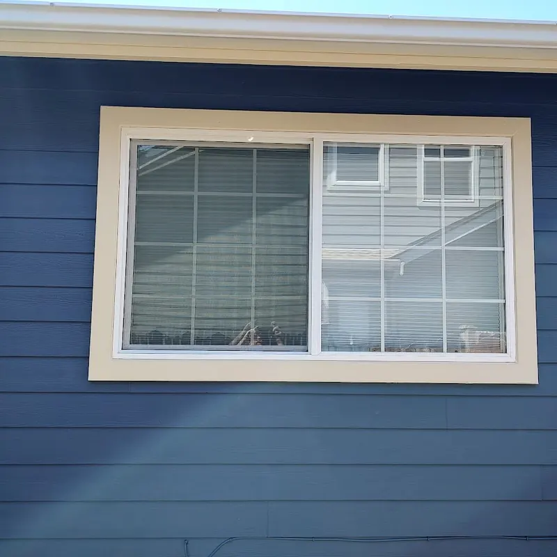 Close-up of a clean cut line between cream window trim and blue siding
